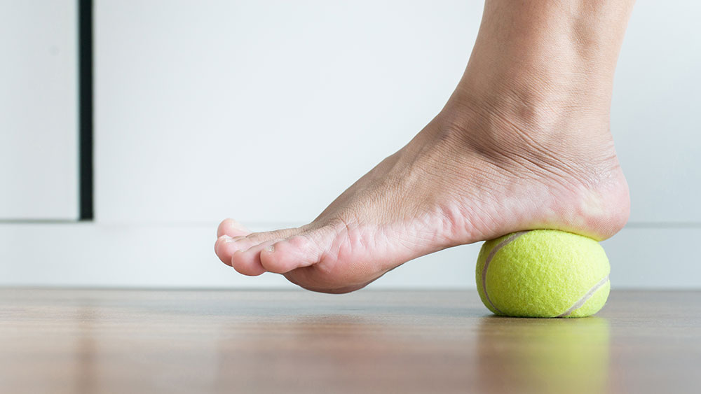 Doing foot exercises with a tennis ball